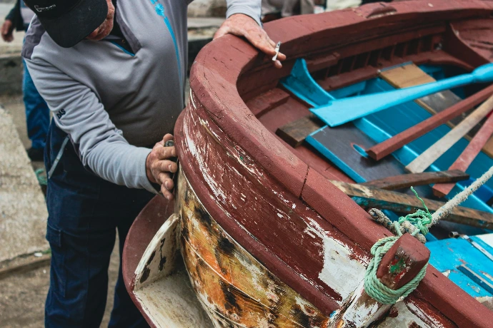 a man standing next to a wooden boat